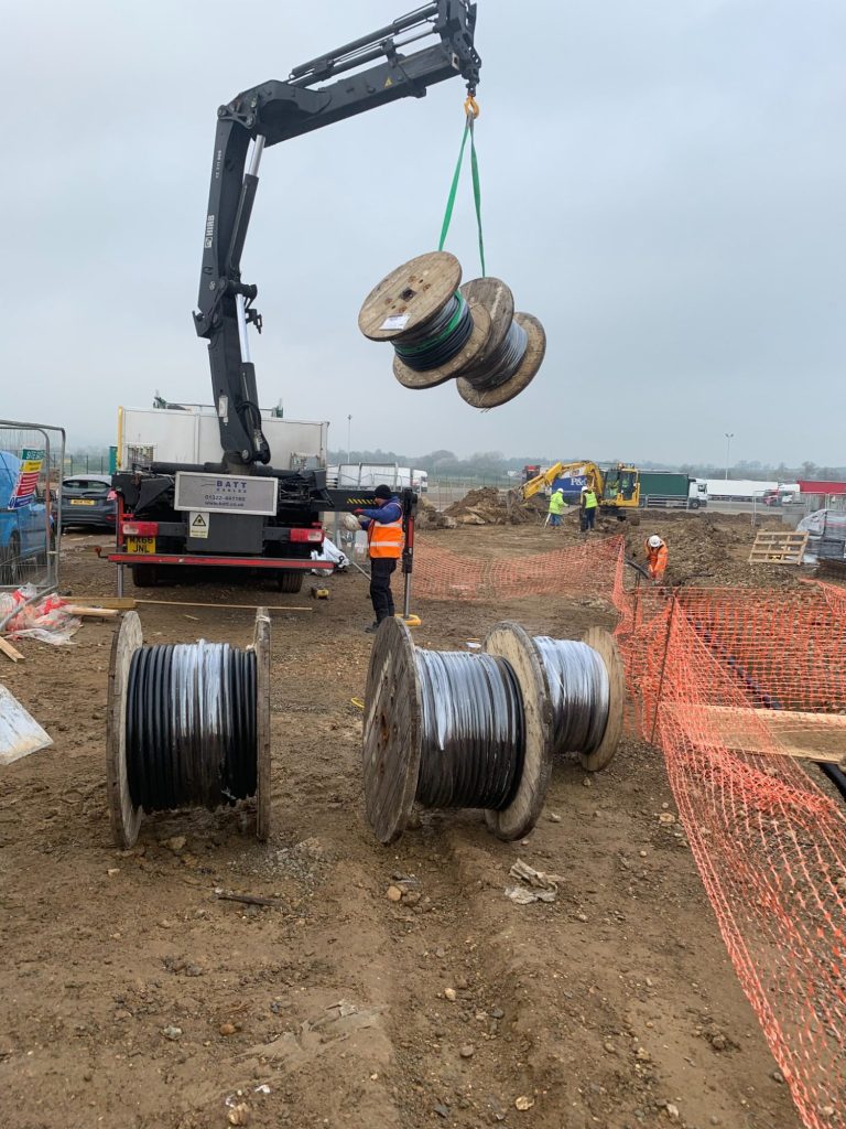 very large and very heavy drums of armoured cable being craned off a delivery lorry