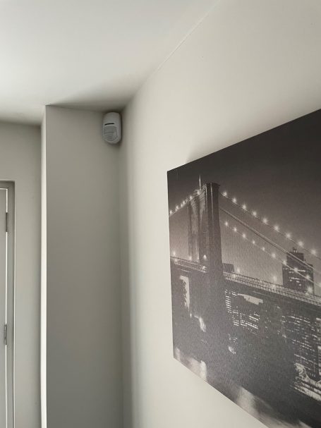 Wireless intruder alarm detector Pyronix KX1 shown mounted in corner of room